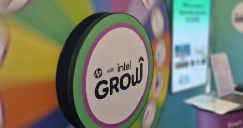 A colorful spinning prize wheel with hp with intel GROW in the center, set up at an event booth with informational displays and banners in the background. BAM Agency