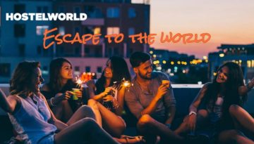 BAM Agency A group of five young people sits on a rooftop at night, holding sparklers and laughing. The city lights are blurred in the background. HOSTELWORLD Escape to the World is visible in the upper left corner, perfectly capturing the essence of todays vibrant youth market. BAM Agency