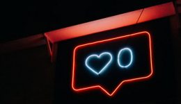 BAM Agency A neon sign against a dark background depicts a red speech bubble with a blue heart and the number zero inside it, capturing the essence of thumb-stopping moments on social media. BAM Agency