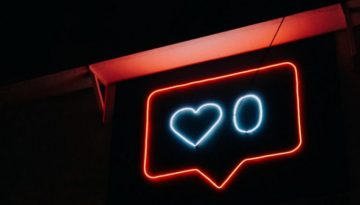 BAM Agency A neon sign against a dark background depicts a red speech bubble with a blue heart and the number zero inside it, capturing the essence of thumb-stopping moments on social media. BAM Agency