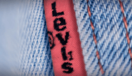 BAM Agency Close-up of blue denim fabric with a red tag that reads Levis in black letters, appealing to the youth market. The stitching is visible, highlighting the texture of the material and emphasizing the brand tag on the denim. BAM Agency