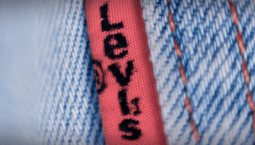 BAM Agency Close-up of blue denim fabric with a red tag that reads Levis in black letters, appealing to the youth market. The stitching is visible, highlighting the texture of the material and emphasizing the brand tag on the denim. BAM Agency