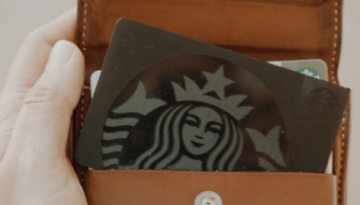 BAM Agency A hand holds an open brown leather wallet, revealing a card with a black and white logo featuring a crowned mermaid, hinting at exclusive loyalty schemes. The wallets interior contrasts against a blurred backdrop, appealing to the savvy youth market. BAM Agency