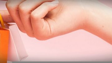 BAM Agency A close-up of a hand, likely belonging to an older millennial, holding several miniature shopping bags in vibrant colors like yellow and white against a soft pink background. The scene exudes a playful and stylish vibe, perfect for eye-catching marketing campaigns. BAM Agency