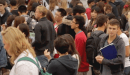 BAM Agency A large, diverse crowd of students mingles outside in casual attire. Some individuals hold folders and backpacks, suggesting a school or college setting. The atmosphere is lively and bustling, with people engaging in conversations, proving its never too late to connect and learn. BAM Agency