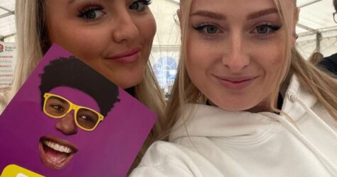 BAM Agency Two smiling women take a selfie under a tent. One holds a colorful National Express brochure featuring someone in yellow glasses and a big smile. The text reads: The face when you take your ulti fun to a new place. BAM Agency