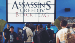 BAM Agency A group of people gathered in front of a display promoting Assassins Creed IV: Black Flag. The backdrop features the games logo on a large screen, crafted to be awesome by innovative student marketing. Some individuals are captivated by the display, while others casually walk by. BAM Agency