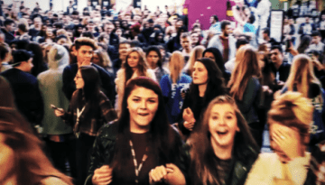 BAM Agency A large crowd of excited people, mostly young women, fills the indoor event, creating a smash of energy. The atmosphere is lively and bustling, fueled by student marketing buzz as individuals express enthusiasm and joy. BAM Agency