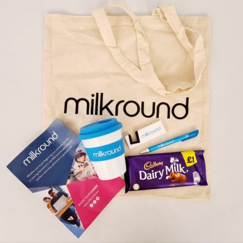 A tote bag with milkround text contains promotional items: a reusable coffee cup, a chocolate bar, a pen, a USB drive, and two flyers. One flyer features people in a workplace setting and text about career opportunities. BAM Agency