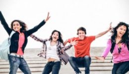 BAM Agency A group of eight freshers joyfully jump in the air with arms raised. They are on stairs, dressed in casual attire, and smiling. The background is a soft, overcast sky, capturing the youthful exuberance of student life. BAM Agency