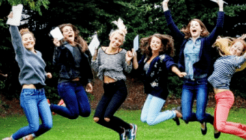 BAM Agency A group of students outdoors, joyfully jumping in the air with trees in the background. They hold white papers and are dressed casually in jeans and jackets, smiling widely. BAM Agency