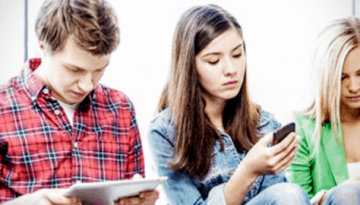 BAM Agency Five people, including members of Generation Z, are sitting in a row, each absorbed in their electronic devices. The group, consisting of both men and women on smartphones and a tablet, exudes a casual atmosphere with relaxed body language and expressions focused on important facts. BAM Agency