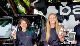 BAM Agency Three smiling freshers stand in front of a truck adorned with a cow model, each holding drinks and tablets. The truck and cow, both branded bam, are part of an exciting experiential campaign. Theyre surrounded by trees, with countless bottles lined up on the truck. BAM Agency