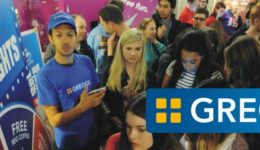 BAM Agency During a bustling Greggs promotional event, a crowd swarms around the booth as part of their Freshers tour. A staff member in a blue Greggs shirt enthusiastically engages with attendees, while the iconic Greggs logo is prominently displayed on the booth. BAM Agency