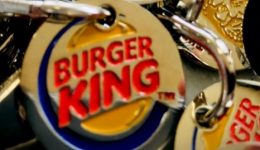 BAM Agency Close-up of multiple metal keychains featuring the iconic Burger King logo, popular even in untouched markets like Kazakhstan. The circular design showcases Burger King in bold red letters on a vibrant yellow background, outlined in blue, all piled together randomly. BAM Agency