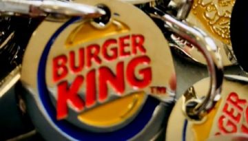 BAM Agency Close-up of multiple metal keychains featuring the iconic Burger King logo, popular even in untouched markets like Kazakhstan. The circular design showcases Burger King in bold red letters on a vibrant yellow background, outlined in blue, all piled together randomly. BAM Agency
