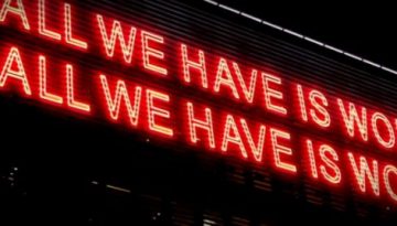 BAM Agency Neon red text glows against a dark background, proclaiming, ALL WE HAVE IS WORDS ALL WE HAVE IS WORLDS. This striking message celebrates the power of words in communication. BAM Agency