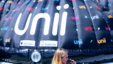 BAM Agency A large black inflatable structure with unii printed in vibrant colors stands impressively in an open indoor space. Crowd gathers, chatting excitedly about the student platforms launch, while signs for the App Store and Mobile Site adorn the eye-catching installation. BAM Agency