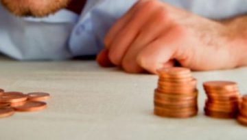 BAM Agency A person in a blue shirt, debunking stereotypes of untidiness, leans over a table with focus and meticulousness, carefully stacking and counting copper coins. BAM Agency