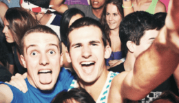 BAM Agency A crowded party scene with young adults smiling and posing for the camera defies wrong assumptions about students. Two men in the center are excited and making silly faces, surrounded by people enjoying the event, creating a lively and energetic atmosphere. BAM Agency
