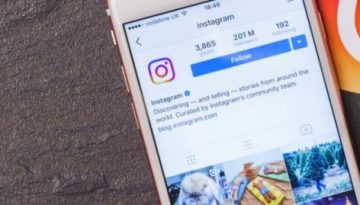 BAM Agency Smartphone displaying Instagram profile on a gray surface, next to an orange Instagram logo card and a vintage Olympus Trip 35 camera, showcasing an Instagrammable brands savvy approach to visual storytelling and effective Instagram marketing. BAM Agency