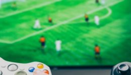 BAM Agency Two millennials engrossed in a soccer video game, gripping a white and a black controller, with the TV screen in the background showcasing their intense rivalry—a true testament to this generation of gamers. BAM Agency