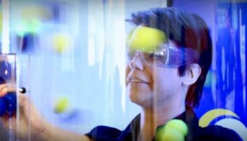 BAM Agency Amid a vibrant blur of colors, a person sporting safety goggles carefully drops yellow and blue balls into a clear vertical tube. This dynamic scene could easily be part of a captivating 2017 youth marketing strategy. BAM Agency