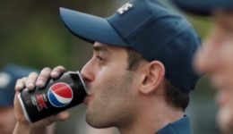 BAM Agency A person in a blue cap enjoys Pepsi Zero Sugar, embodying the vibe of a dynamic Youth Experiential Campaign. In the background, other similarly capped individuals blend into the slightly out-of-focus outdoor setting, each moment capturing the spirit of youthful adventure. BAM Agency