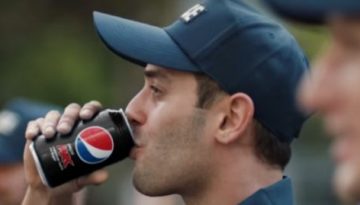 BAM Agency A person in a blue cap enjoys Pepsi Zero Sugar, embodying the vibe of a dynamic Youth Experiential Campaign. In the background, other similarly capped individuals blend into the slightly out-of-focus outdoor setting, each moment capturing the spirit of youthful adventure. BAM Agency