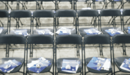 BAM Agency Rows of empty black folding chairs in the auditorium, each with a blue program booklet ready for the freshers to begin their journey. BAM Agency