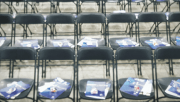 BAM Agency Rows of empty black folding chairs in the auditorium, each with a blue program booklet ready for the freshers to begin their journey. BAM Agency